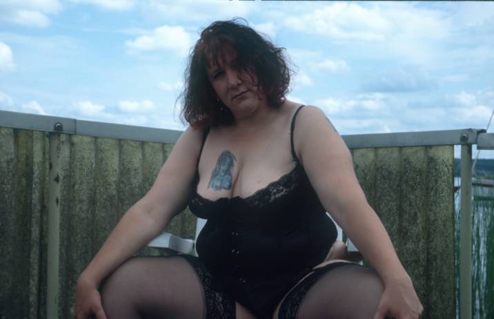 fette Frau mit tätowierter Brust in Strapse