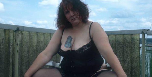fette Frau mit tätowierter Brust in Strapse