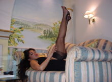 Frau in Strapsen streckt die Beine hoch auf der Couch